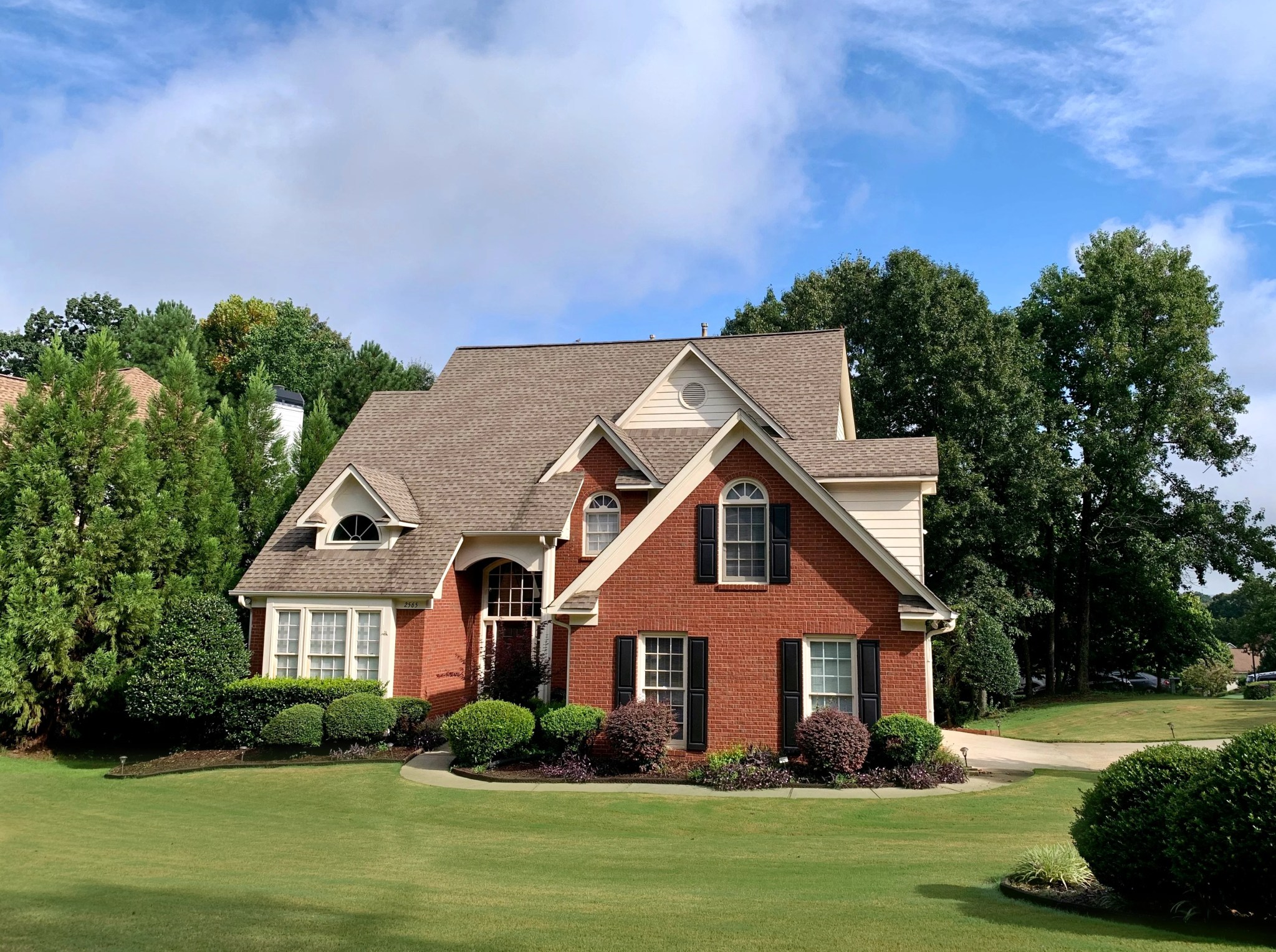 red brick home with nice green grass and garden beds